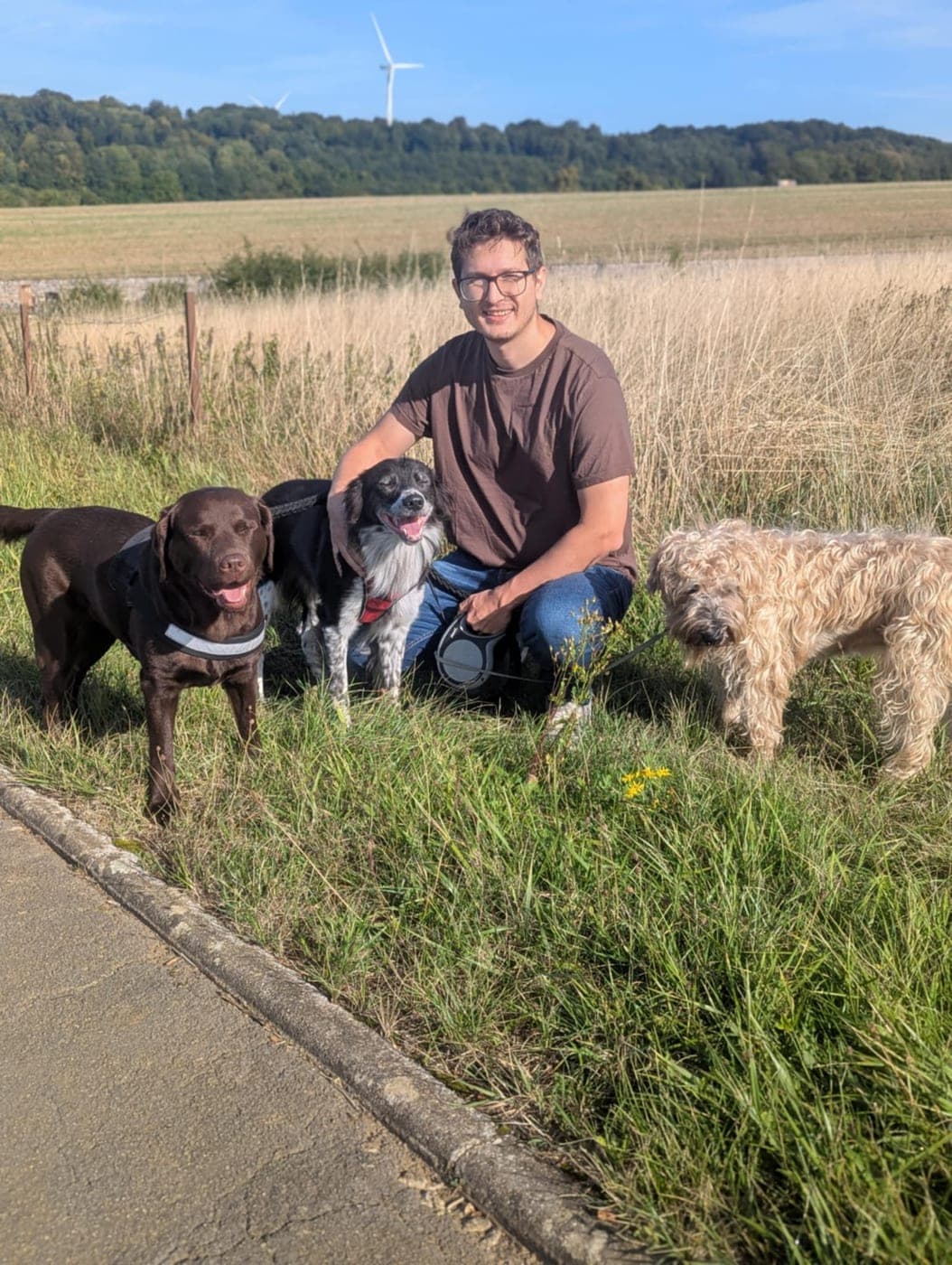 Halte dans les champs autour de Crusnes : notre hôte accroupi dans les herbes hautes avec trois chiens