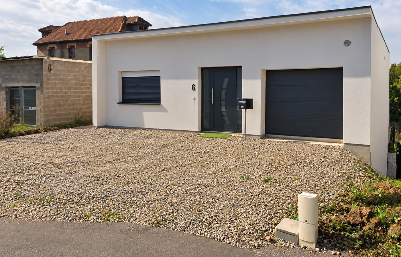 La maison de Zen & Wouaf à Crusnes vue de la rue : façade blanche, porte d'entrée et garage anthracite